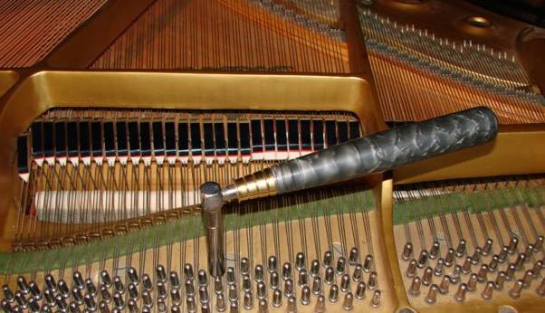 A tuning hammer on the tuning pins of a grand piano
