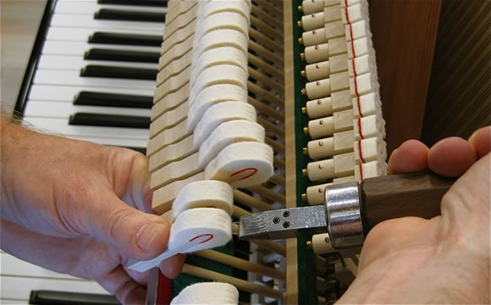 A technician working on upright piano hammers
